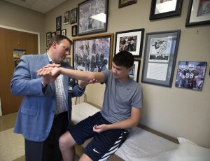 Orthopedic doctor examining young athlete's elbow