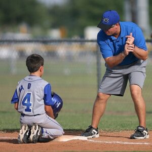 Baseball coach demonstrating swing to young ball player